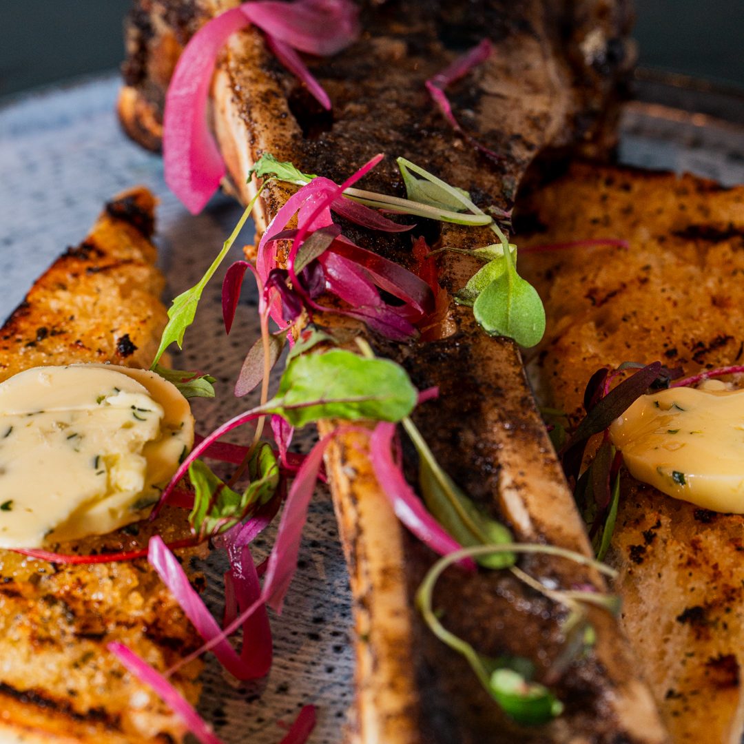 Grilled meat with herbs, garnished with pink onions and sauce, on a plate in a London restaurant 