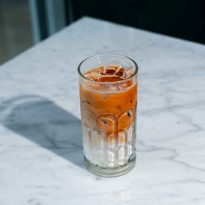 Iced coffee drink with cream layers in a tall glass on a marble surface in london 