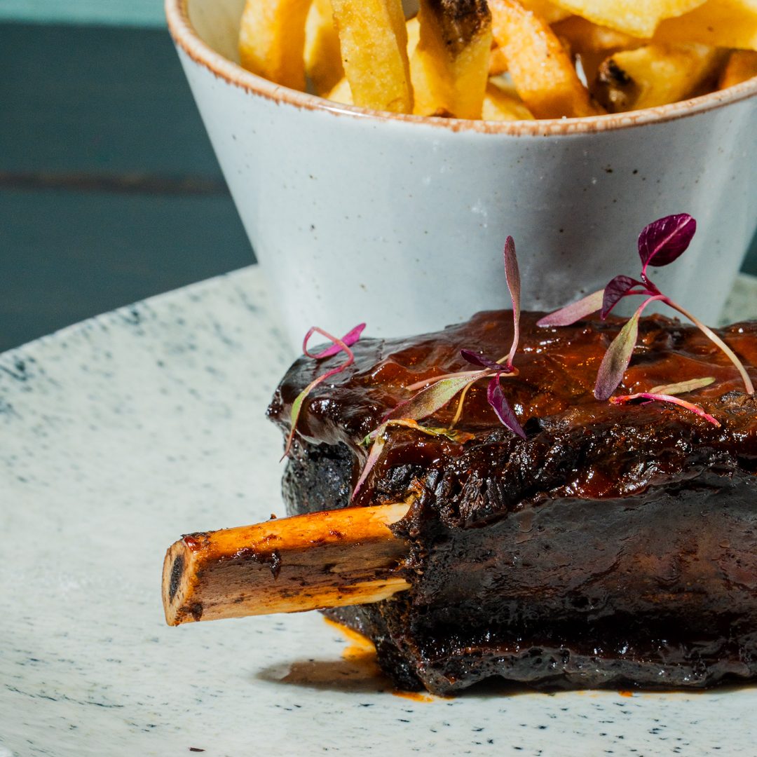 Braised beef short rib served with crispy chips and garnished with microgreens in the London Restaurant