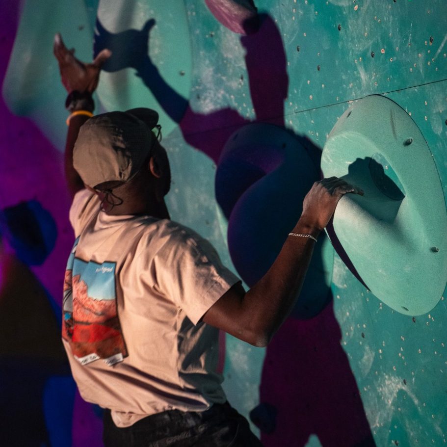 A climber reaching for handholds on a colourful climbing wall in lLondon