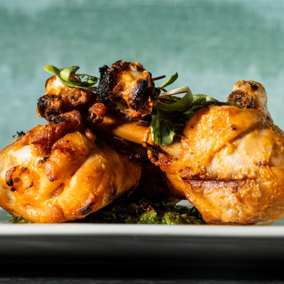 Grilled chicken legs garnished with green herbs on a white plate in london Restaurant