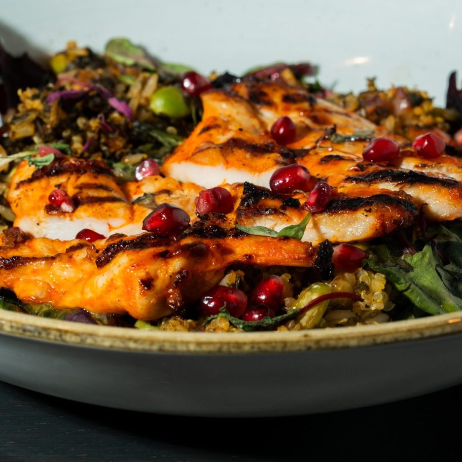 Grilled chicken on a bed of mixed greens, garnished with pomegranate seeds in London Restaurant